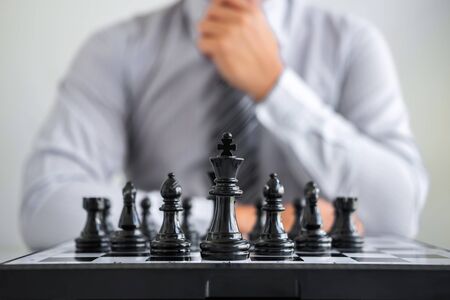Black and White chess with player, Hands of businessman thinking to moving chess figure in competition and planning strategy to success play for win.の写真素材