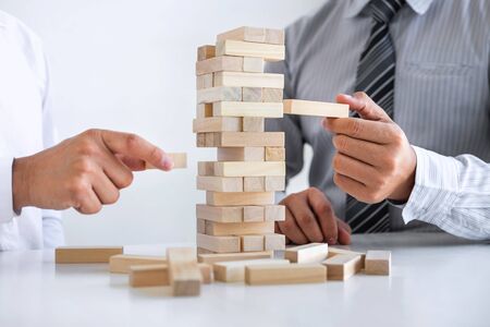 Planning Risk and Strategy in Business, Image of two Businessman hand placing making wooden block...