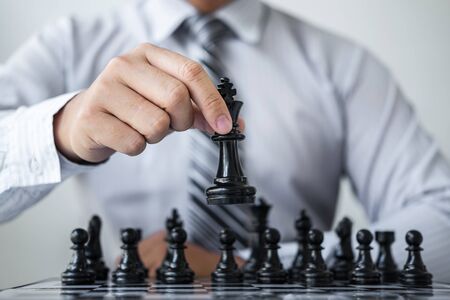 Black and White chess with player, Hands of businessman thinking to moving chess figure in competition and planning strategy to success play for win.の写真素材