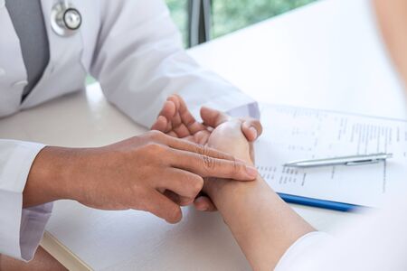 Doctor checking measuring pressure on patient's hand pulse by hands, Medical and healthcare concept.