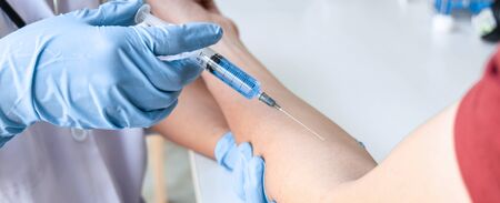 Doctor making a vaccination into patient with needle getting immune vaccine at arm for flu shot, coronavirus protective of epidemic.の写真素材