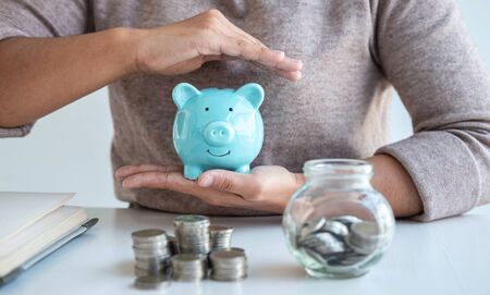 Young woman hands protection piggy bank and planning growing saving to strategy with pile coins for future plan fund of travel, education, home and retirement.の写真素材