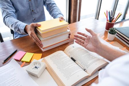 Teaching helping and study course, Team of young teacher or tutor helps students to learning in classroom for homework a test or exam at desk with papers.の写真素材