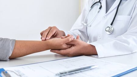 Doctor checking measuring pressure on patient's hand pulse by hands, Medical and healthcare concept.