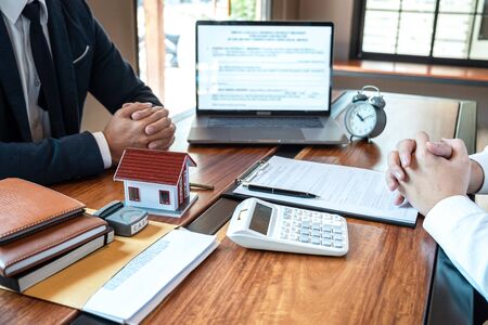 Sale purchase contract to buy a house, Real estate agent are presenting home loan and giving keys to customer after signing contract to buy house with approved property application form.の写真素材