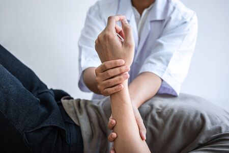 Female Physiotherapist working examining treating injured arm of athlete male patient, stretching and exercise, Doing the Rehabilitation therapy pain in clinic.の写真素材