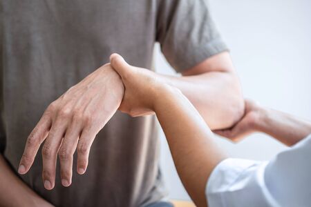 Doctor or Physiotherapist working examining treating injured arm of athlete male patient, stretching...