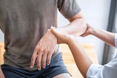 Female Physiotherapist working examining treating injured arm of athlete male patient, stretching and exercise, Doing the Rehabilitation therapy pain in clinic.の写真素材