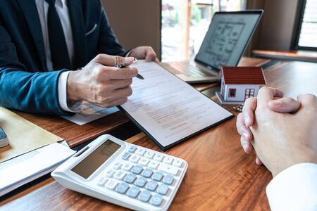 Sale purchase contract to buy a house, Real estate agent are presenting home loan and giving keys to customer after signing contract to buy house with approved property application form.の写真素材