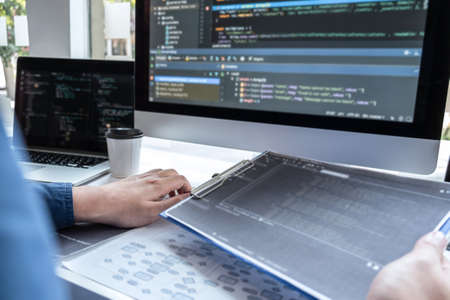 Developer programmer working on project in software development computer in IT company office, Writing codes and data code website and coding database technologies to find solution to problem.の写真素材