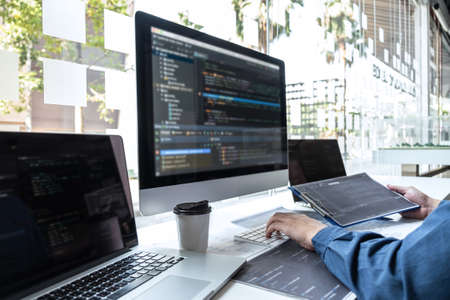 Developer programmer working on project in software development computer in IT company office, Writing codes and data code website and coding database technologies to find solution to problem.の写真素材