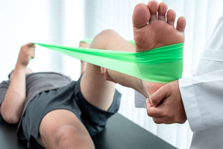 Physiotherapist working examining treating injured leg of athlete patient, Doctor doing the Rehabilitation therapy pain in clinic.の写真素材