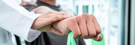 Physiotherapist working examining treating injured arm of athlete patient, stretching and exercise,...