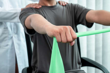 Female Physiotherapist working examining treating injured arm of athlete patient, stretching and...