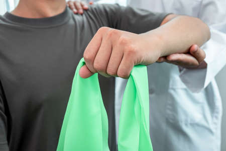 Physiotherapist working examining treating injured arm of athlete patient, stretching and exercise, Doctor doing the Rehabilitation therapy pain in clinic.の写真素材