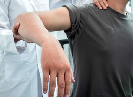 Female Physiotherapist working examining treating injured arm of athlete patient, stretching and...