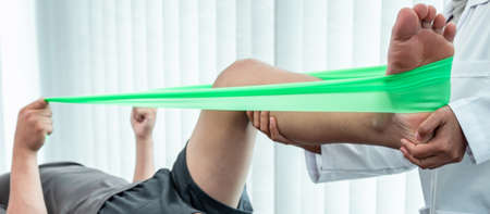Female Physiotherapist working examining treating injured leg of patient, Doing exercises the...