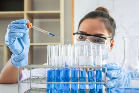 Female scientific researcher or doctor working in laboratory about virus and vaccine antiretroviral coronavirus covid19 researcher investigations with test tubes flask and blue liquid solution.の写真素材