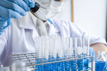 Female scientific researcher or doctor working in laboratory about virus and vaccine antiretroviral coronavirus covid19 researcher investigations with test tubes flask and blue liquid solution.の写真素材