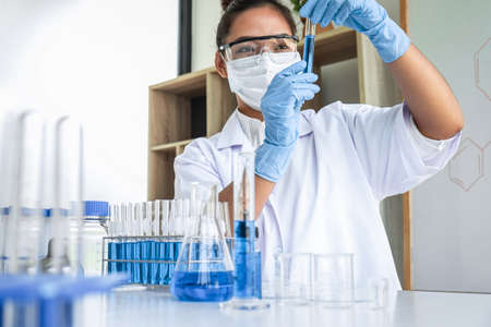 Female scientific researcher or doctor working in laboratory about virus and vaccine antiretroviral coronavirus covid19 researcher investigations with test tubes flask and blue liquid solution.の写真素材