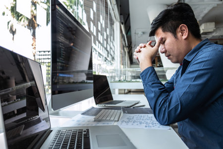 Man Programmer stressed and headache project in software development computer in IT company office, Writing codes and data code website and coding database technologies to find solution.の写真素材