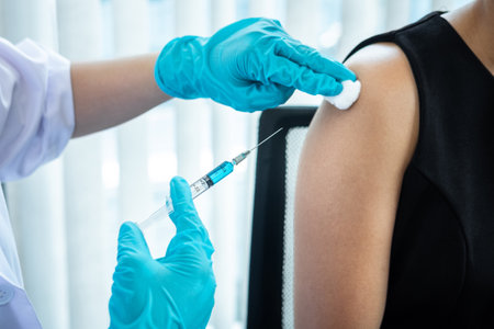 Doctor making a vaccination into patient with needle getting immune vaccine at arm for flu shot,...
