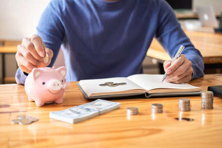 Young man putting coins into piggy bank planning growing saving to strategy with money box for...