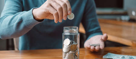 Young man putting coins into bottle planning growing saving to strategy with money box for future...