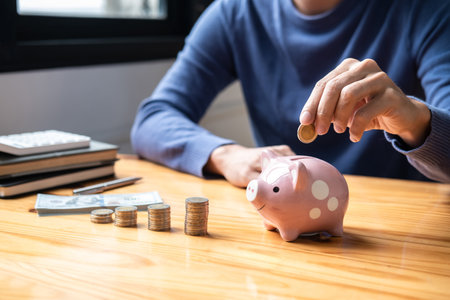 Young man putting coins into piggy bank planning growing saving to strategy with money box for future plan fund of travel, education, home and retirement.の写真素材