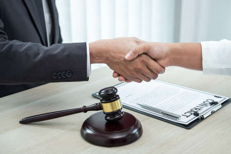 Male lawyer shaking hands with client after good deal negotiation cooperation meeting in courtroom.の写真素材