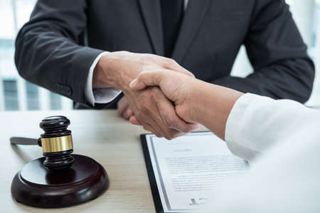 Male lawyer shaking hands with client after good deal negotiation cooperation meeting in courtroom.の写真素材