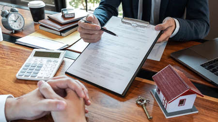 Real estate agent are presenting home loan and sending keys to customer after signing contract to...