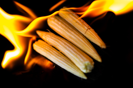 Burning baby corn on black background