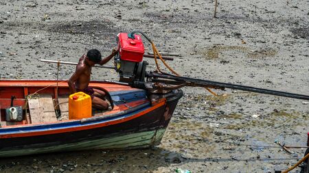 Moken man is repairing boat engines in Moken Village Thailand