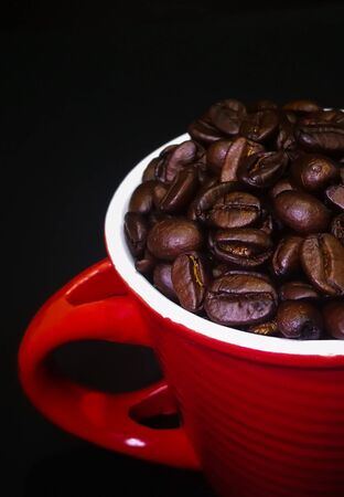 Roasted Coffee Beans in Red cup isolated black backgroundの写真素材