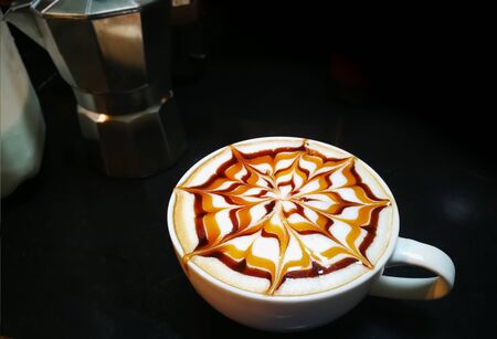 homemade latte art coffee with chocolate sauce and caramel sauce  on Milk foam in kitchen. Lined pattern Flower  on latte art coffee.の写真素材