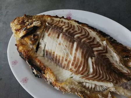 Salt-Burning Fish on white dish, healthy food and weight control. Food on marble surface.