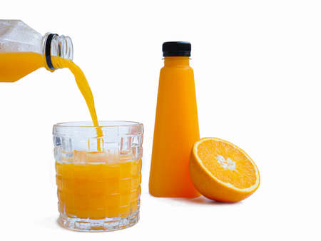 Pour the orange juice in a glass jar on a white background and have the orange juice bottle ready. Orange cut in half as backgroundの写真素材
