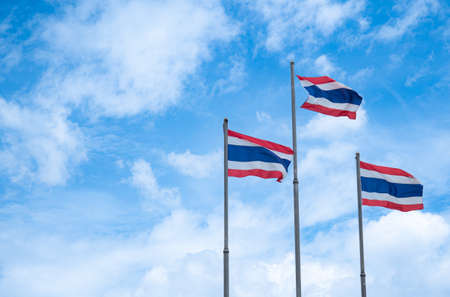 The flag of Thailand on a high pole with a bright sky and white clouds background.の写真素材