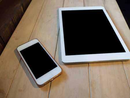 top view image of smartphone and tablet device over wooden table