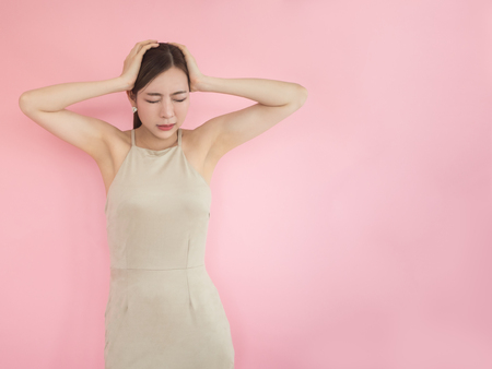 Worried Woman Touching Head on pink backgroundの写真素材