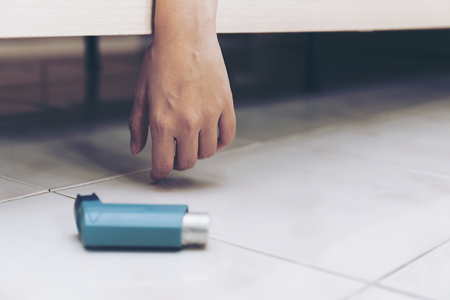 Hand of women suffering asthma attack reaching inhaler sleep on a couch in the living room at home. first aid for asthma disease person,treatment or prevention of Bronchospasm in adult and kid conceptの写真素材