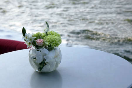 A vase of flowers on the table against the seaの写真素材