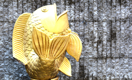 Golden Fish sculpture on the brick wall - select focus on fishの写真素材