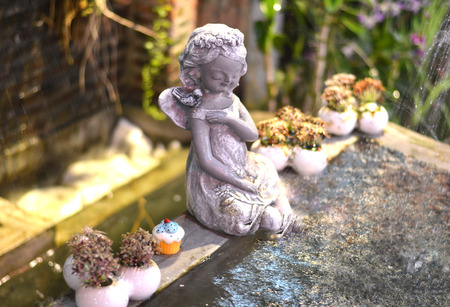 Girl childern statue sitting on the water fountain - select focus on face statueの写真素材