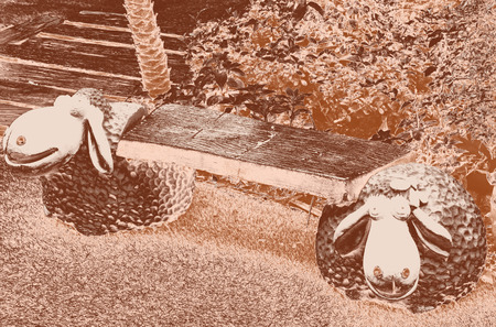 A seat in the green garden background with two sheep statue - select focus on seatの写真素材