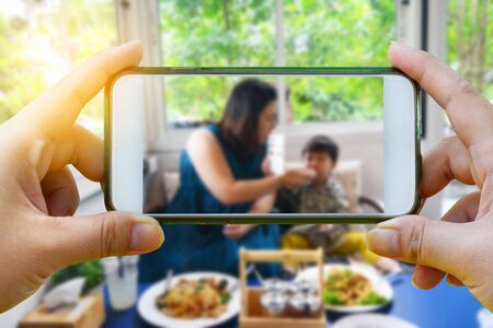 Take a photo with smartphone on Portrait asian boy and his mother in the restaurant background - Mother 's day conceptの写真素材