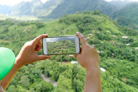 Traveler take a photo green tree mountain by smartphone on long holiday - Traveling and Holiday of conceptの写真素材