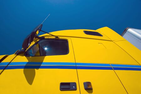 Wide angle view of yellow transport truck from below looking upwards into blue skyの写真素材