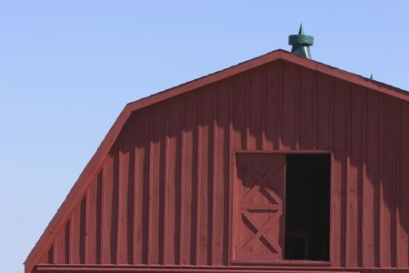 Second floor door of a red barn against a blue skyの写真素材